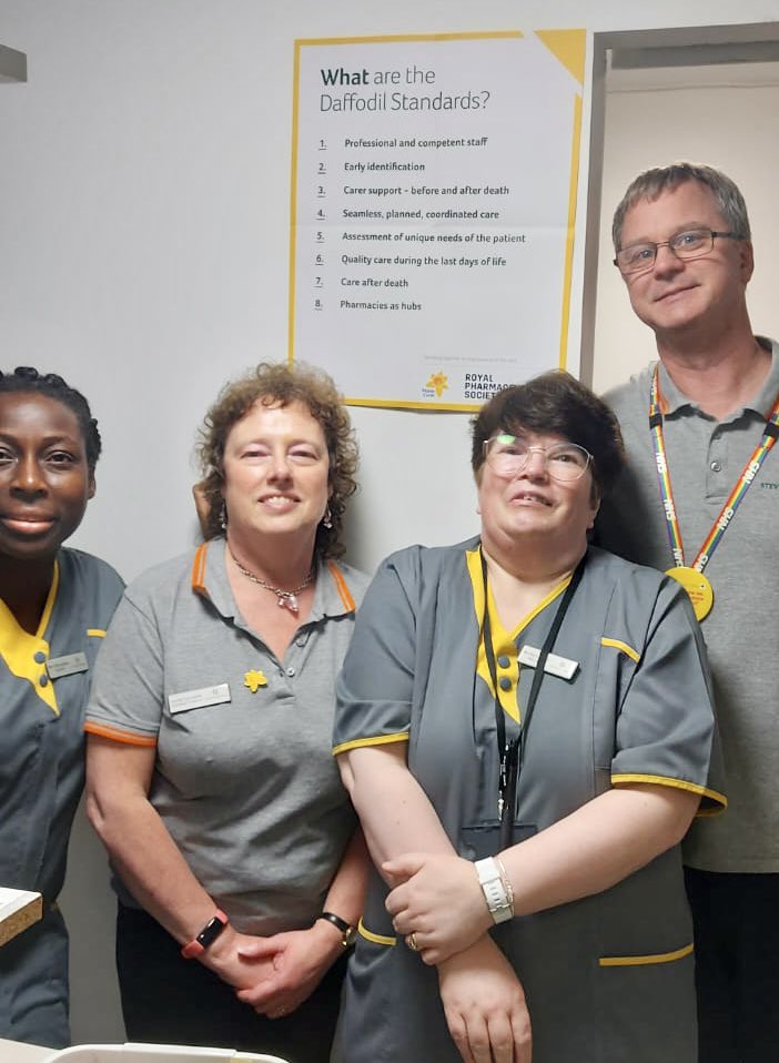 group picture of Wells Pharmacy infront of Daffodil Standards poster