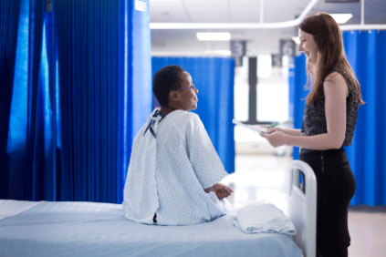 Photo of a pharmacist attending to a hospital patient at their bedside Photo of a pharmacist attending to a hospital patient at their bedside